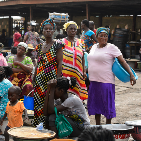 ELMINA, GHANA -JAN 18, 2017: Unidentified  Ghanaian women in colored clothes gather near Elmina port. People of Ghana suffer of poverty due to the bad economyのeditorial素材