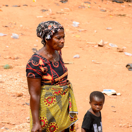 ELMINA, GHANA -JAN 18, 2017: Unidentified  Ghanaian woman walks with a child on the street in...