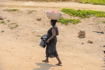 ELMINA, GHANA -JAN 18, 2017: Unidentified  Ghanaian woman walks along the market of Elmina . People of Ghana suffer of poverty due to the bad economyのeditorial素材