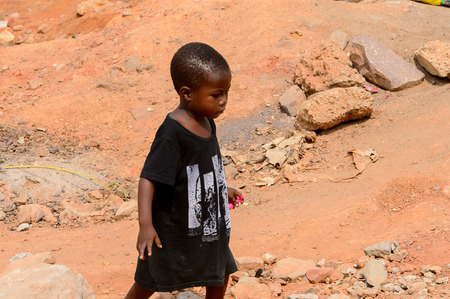 ELMINA, GHANA -JAN 18, 2017: Unidentified  Ghanaian little boy in black shirt walks on the street in Elmina. Children of Ghana suffer of poverty due to the bad economyのeditorial素材
