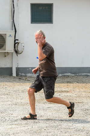 CENTRAL REGION, GHANA - Jan 17, 2017: Unidentified European tourist runs in local village.のeditorial素材