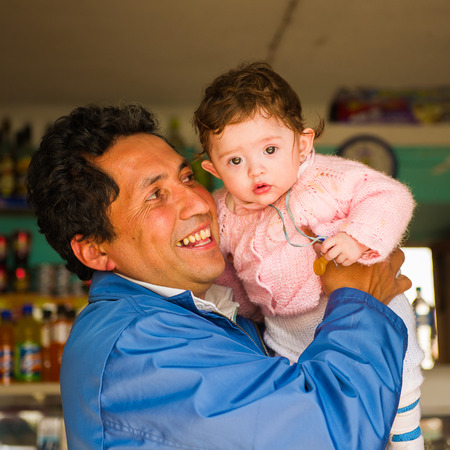 PERU - NOVEMBER 3, 2010: Unidentified happy father shop owner holds his baby boy in his hands in Peru, Nov 3, 2010. Over 50 per cent of people in Peru live below the the poverty line.のeditorial素材