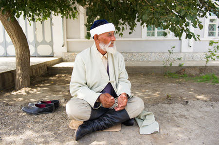 BUKHARA, UZBEKISTAN - JUNE 7, 2011: Unidentified Uzbek man sits on the ground in Uzbekistan, Jun 7,...