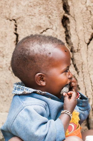 AMBOSELI, KENYA - OCTOBER 10, 2009: Portrait of an unidentified Massai little boy trying to put everything in the mouth Kenya, Oct 10, 2009. Massai people are a Nilotic ethnic groupのeditorial素材