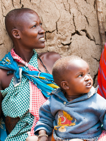 AMBOSELI, KENYA - OCTOBER 10, 2009: Unidentified Massai woman holds her litle baby on her knees in...
