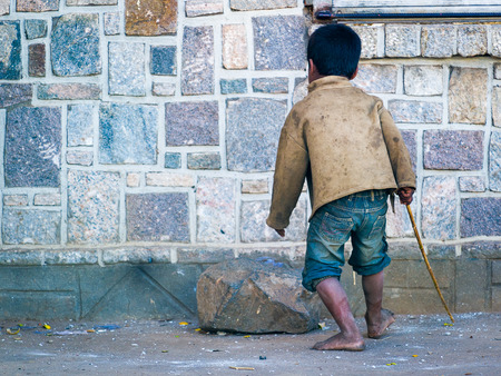 ANTANANARIVO, MADAGASCAR - JUNE 29, 2011: Unidentified Madagascar little boy with a wooden stick plays in the street. People in Madagascar suffer of poverty due to the slow development of the countryのeditorial素材
