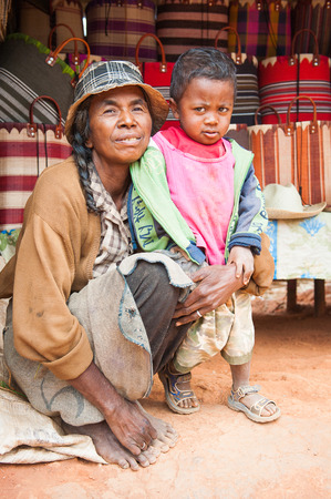 ANTANANARIVO, MADAGASCAR - JUNE 29, 2011: Unidentified Madagascar woman with her baby sits in the street with a deep expression. People in Madagascar suffer of poverty due to the slow development of the countryのeditorial素材
