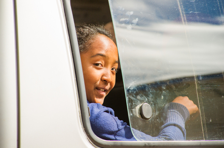 ANTANANARIVO, MADAGASCAR - JUNE 30, 2011: Unidentified Madagascar girl smiles out the window. People in Madagascar suffer of poverty due to the slow development of the countryのeditorial素材