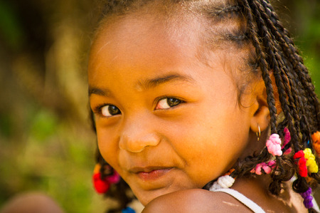 MADAGASCAR - JUNE 27, 2011: Unidentified Madagascar girl with curly hair smiles for the camera in Madagascar, June 27, 2011. Children of Madagascar suffer of poverty due to the unstable situation.のeditorial素材