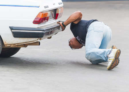 ANTANANARIVO, MADAGASCAR - JUNE 28, 2011: Unidentified Madagascar man looks something under the car. People in Madagascar suffer of poverty due to the slow development of the countryのeditorial素材