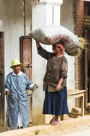 ANTANANARIVO, MADAGASCAR - JUNE 29, 2011: Unidentified Madagascar woman carries a big bag of hay. People in Madagascar suffer of poverty due to the slow development of the countryのeditorial素材