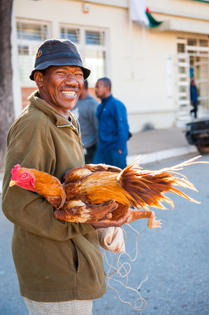 ANTANANARIVO, MADAGASCAR - JUNE 30, 2011: Unidentified Madagascar man holds a hen his hands.  People in Madagascar suffer of poverty due to slow development of the countryのeditorial素材