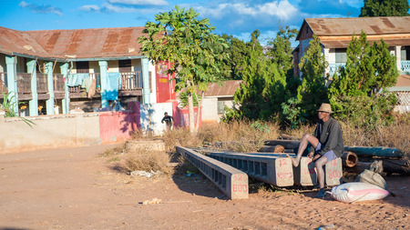 ANTANANARIVO, MADAGASCAR - JULY 1, 2011: Unidentified Madagascar man sits in the street near the house. People in Madagascar suffer of poverty due to slow development of the countryのeditorial素材
