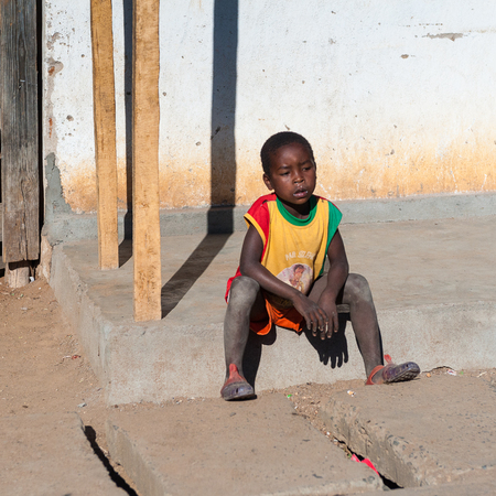 ANTANANARIVO, MADAGASCAR - JULY 3, 2011: Unidentified Madagascar boy sits near a house. People in Madagascar suffer of poverty due to slow development of the countryのeditorial素材