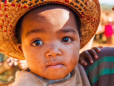 MADAGASCAR - JULY 1, 2011: Portrait of an unidentified little baby girl in a Mexican sombrero hat in Madagascar, July 1, 2011. Children of Madagascar suffer of poverty due to the unstable situation.のeditorial素材