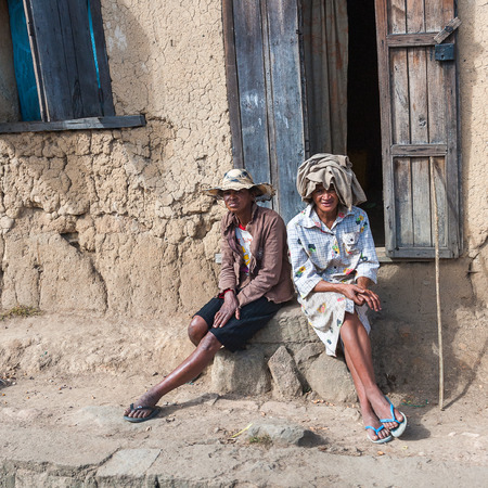 ANTANANARIVO, MADAGASCAR - JUNE 30, 2011: Unidentified Madagascar men sit on a porch. People in Madagascar suffer of poverty due to slow development of the countryのeditorial素材