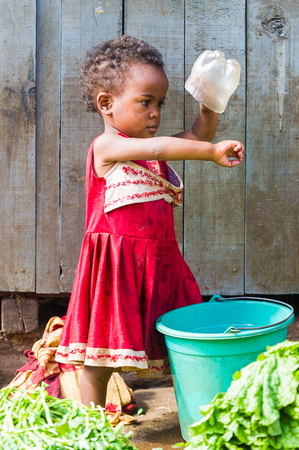 ANTANANARIVO, MADAGASCAR - JUNE 30, 2011: Unidentified Madagascar little girl plays with water. People in Madagascar suffer of poverty due to slow development of the countryのeditorial素材