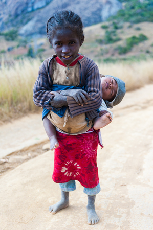 ANTANANARIVO, MADAGASCAR - JULY 1, 2011: Unidentified Madagascar girl holds her little brother. People in Madagascar suffer of poverty due to slow development of the countryのeditorial素材