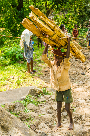 OMO, ETHIOPIA - SEPTEMBER 19, 2011: Unidentified Ethiopian boy carries wood. People in Ethiopia suffer of poverty due to the unstable situationのeditorial素材