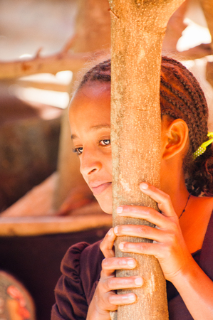 OMO, ETHIOPIA - SEPTEMBER 20, 2011: Unidentified Ethiopian beautiful girl stays near a wooden trunk. People in Ethiopia suffer of poverty due to the unstable situationのeditorial素材
