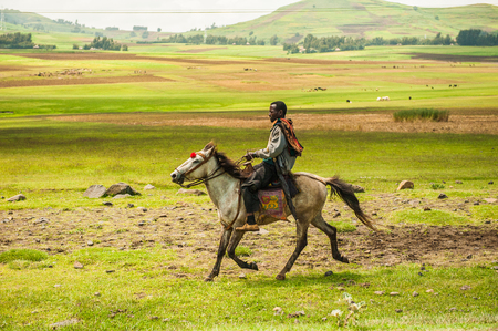 OMO, ETHIOPIA - SEPTEMBER 19, 2011: Unidentified Ethiopian man rides a horse in open field. People...