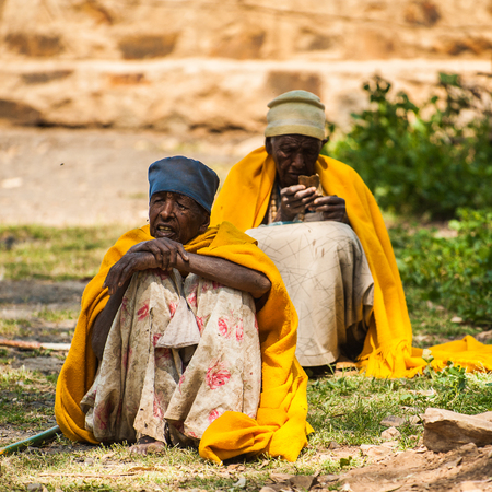 AKSUM, ETHIOPIA - SEPTEMBER 24, 2011: Unidentified Ethiopian men sit with a yellow blanket. People in Ethiopia suffer of poverty due to the unstable situationのeditorial素材