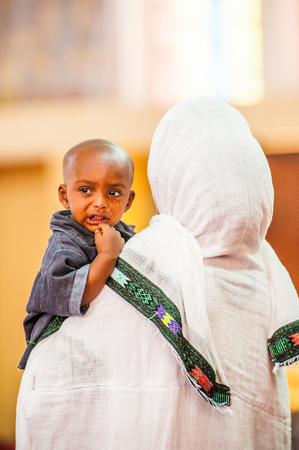 OMO, ETHIOPIA - SEPTEMBER 21, 2011: Unidentified Ethiopian woman in white tissue and her baby in the street. People in Ethiopia suffer of poverty due to the unstable situationのeditorial素材