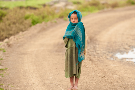 AKSUM, ETHIOPIA - SEPTEMBER 22, 2011: Unidentified Ethiopian girl walks over the road. People in Ethiopia suffer of poverty due to the unstable situationのeditorial素材