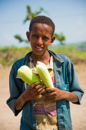 AKSUM, ETHIOPIA - SEPTEMBER 22, 2011: Unidentified Ethiopian boy sells maiz in the desert. People in Ethiopia suffer of poverty due to the unstable situationのeditorial素材