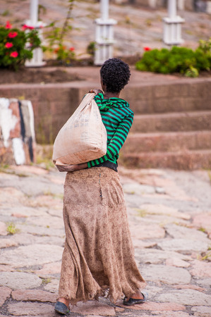 OMO, ETHIOPIA - SEPTEMBER 21, 2011: Unidentified Ethiopian woman walks with a bag in the street. People in Ethiopia suffer of poverty due to the unstable situationのeditorial素材