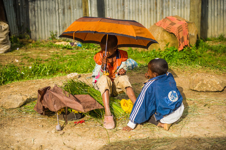 OMO, ETHIOPIA - SEPTEMBER 21, 2011: Unidentified Ethiopian girl boy sits under an umbrella. People in Ethiopia suffer of poverty due to the unstable situationのeditorial素材