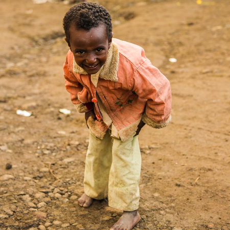 LALIBELA, ETHIOPIA - SEPTEMBER 28, 2011: Unidentified Ethiopian little boy dances for the camera wearing pink shirt and white trousers. People in Ethiopia suffer of poverty due to the unstable situationのeditorial素材