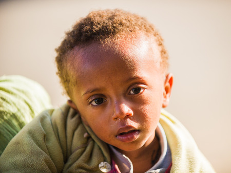 LALIBELA, ETHIOPIA - SEPTEMBER 28, 2011: Unidentified Ethiopian girl watches the camera. People in...