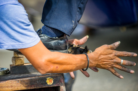 SAN JOSE, COSTA RICA - JAN 6, 2012: Unidentified Costa Rican man cleans shoes to the other man. 65.8% of Costa Rican people belong to the White (Castizo) ethnic groupのeditorial素材