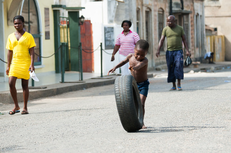 GHANA - MARCH 2, 2012: Unindentified Ghanaian boy plays with a car tire on the street in Ghana, on March 2nd, 2012. People in Ghana suffer from poverty due to the slow development of the countryのeditorial素材