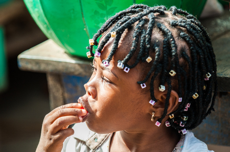 ACCRA, GHANA - MARCH 4, 2012: Unidentified Ghanaian beautiful girl with  cute pigtails in the street in Ghana. Children of Ghana suffer of poverty due to the unstable economic situationのeditorial素材