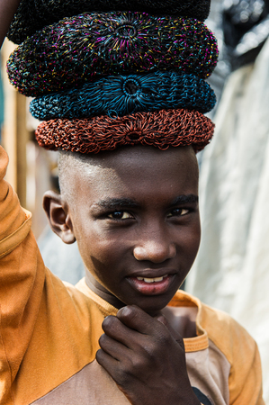 ACCRA, GHANA - MARCH 4, 2012: Unidentified Ghanaian boy sells hats at the market in Ghana. People of Ghana suffer of poverty due to the unstable economic situationのeditorial素材