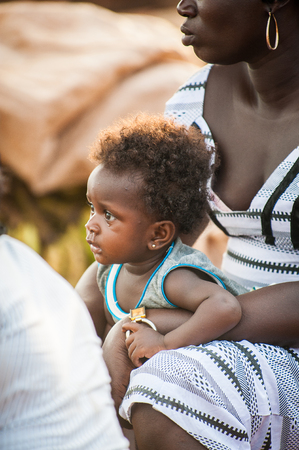 ACCRA, GHANA - MARCH 5, 2012: Unidentified Ghanaian baby boy on his mother lap in the street in Ghana. Children of Ghana suffer of poverty due to the unstable economic situationのeditorial素材