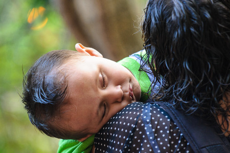 MEXICO CITY, MEXICO - DEC 29, 2011: Unidentified Mexican little boy sleeps on his mother shoulders. 60% of Mexican people belong to the Mestizo ethnic groupのeditorial素材