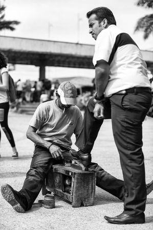 SAN JOSE, COSTA RICA - JAN 6, 2012: Unidentified Costa Rican man cleans shoes to the other man. 65.8% of Costa Rican people belong to the White (Castizo) ethnic groupのeditorial素材