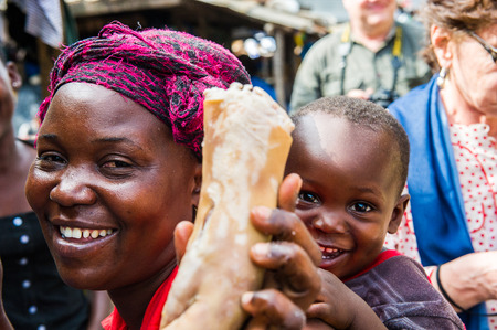 ACCRA, GHANA - MARCH 4, 2012: Unidentified Ghanaian woman with pork legs and her smiling baby in Ghana. People of Ghana suffer of poverty due to the unstable economic situationのeditorial素材