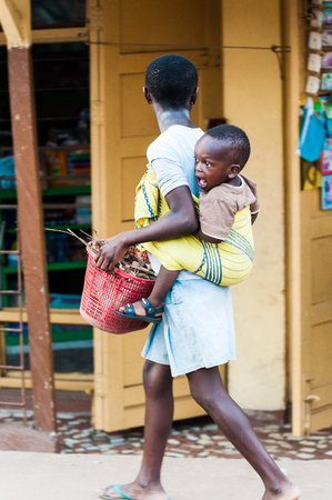 ACCRA, GHANA - MARCH 3, 2012: Unidentified Ghanaian woman carries her little baby on her back in Ghana. People of Ghana suffer of poverty due to the unstable economic situationのeditorial素材