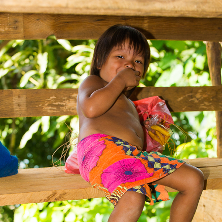 EMBERA VILLAGE, PANAMA, JANUARY 9, 2012: Unidentified native Indian girl eats bananas in a cabin in Panama, Jan 9, 2012. Indian reservation is the way to conserve native culture, languange, traditionsのeditorial素材