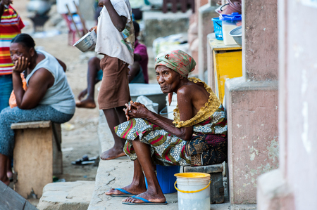 ACCRA, GHANA - MARCH 3, 2012: Unidentified Ghanaian old woman sits at the porch in Ghana. People of Ghana suffer of poverty due to the unstable economic situationのeditorial素材