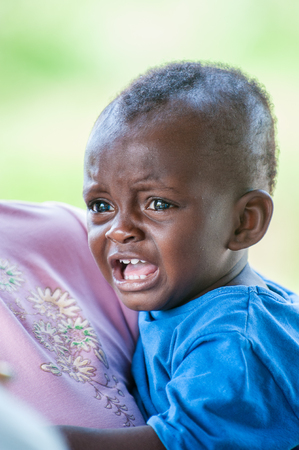 ACCRA, GHANA - MARCH 3, 2012: Unidentified Ghanaian little baby boy on his mothers back in Ghana. People of Ghana suffer of poverty due to the unstable economic situationのeditorial素材