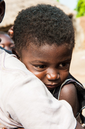ACCRA, GHANA - MARCH 6, 2012: Unidentified Ghanaian little boy on his brother back in the street in Ghana. Children of Ghana suffer of poverty due to the unstable economic situationのeditorial素材