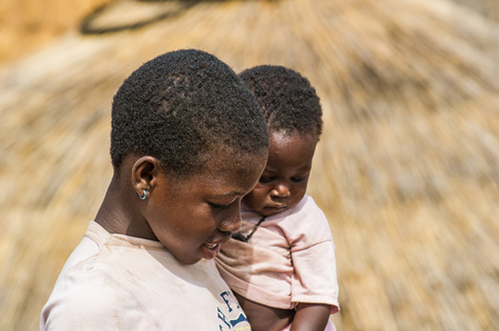 ACCRA, GHANA - MARCH 6, 2012: Unidentified Ghanaian woman carries her little baby in the street in Ghana. Children of Ghana suffer of poverty due to the unstable economic situationのeditorial素材