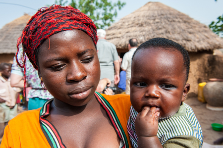 ACCRA, GHANA - MARCH 6, 2012: Unidentified Ghanaian woman carries her little baby in the street in Ghana. Children of Ghana suffer of poverty due to the unstable economic situationのeditorial素材