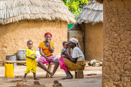 ACCRA, GHANA - MARCH 6, 2012: Unidentified Ghanaian women and their children on a bench near their house in the street in Ghana. Children of Ghana suffer of poverty due to the unstable economic situationのeditorial素材