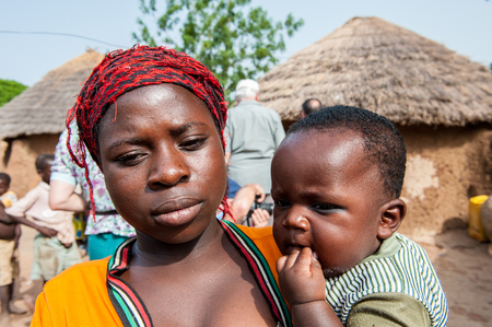 ACCRA, GHANA - MARCH 6, 2012: Unidentified Ghanaian woman carries her little baby in the street in Ghana. Children of Ghana suffer of poverty due to the unstable economic situationのeditorial素材